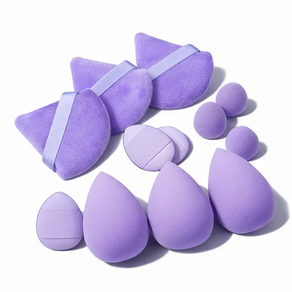 Set of purple makeup sponges and powder puffs in various shapes on a white background