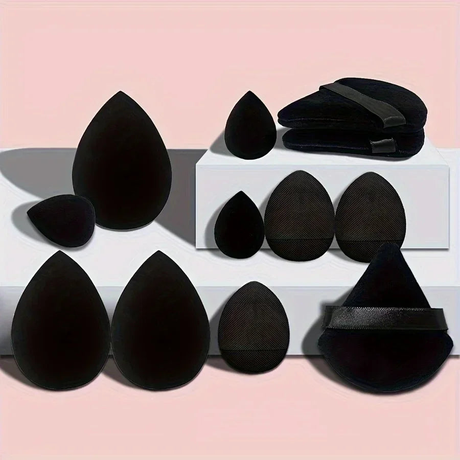 Black makeup sponge and puff set arranged on white blocks against a pink background